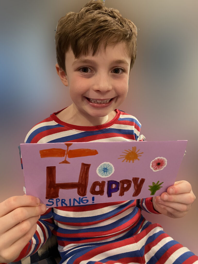 Child holding "Happy Spring" greeting card.